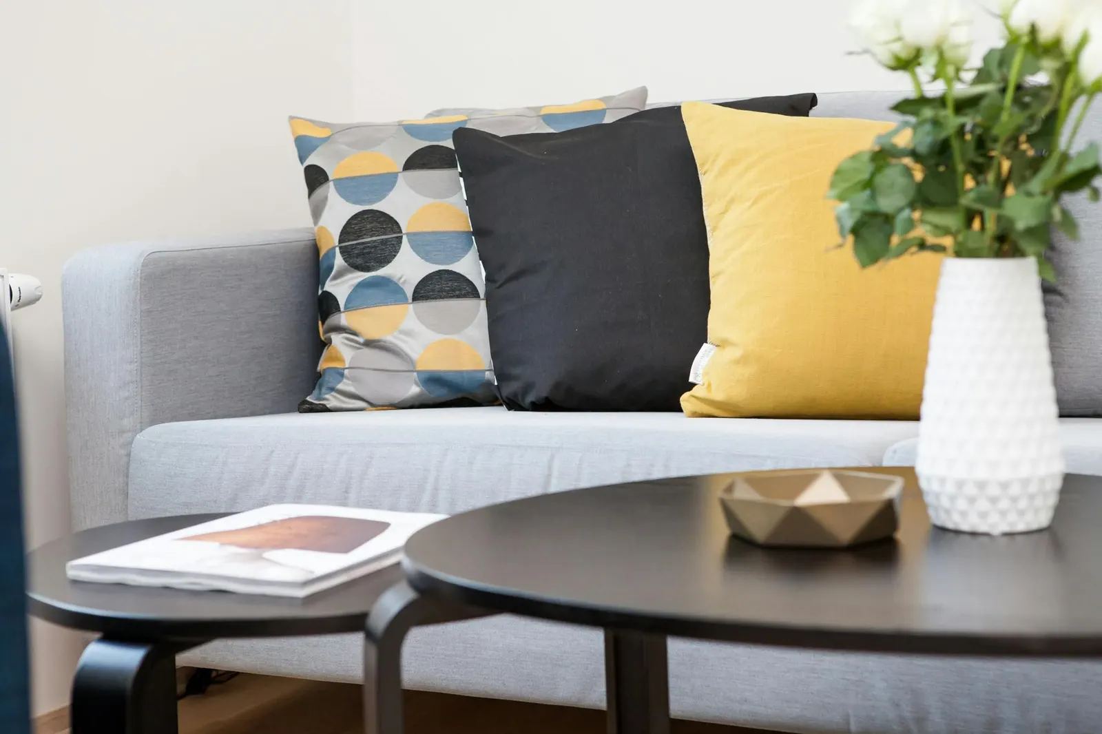 Sala con sofá beige, base de madera, mesas doradas y puf tejido