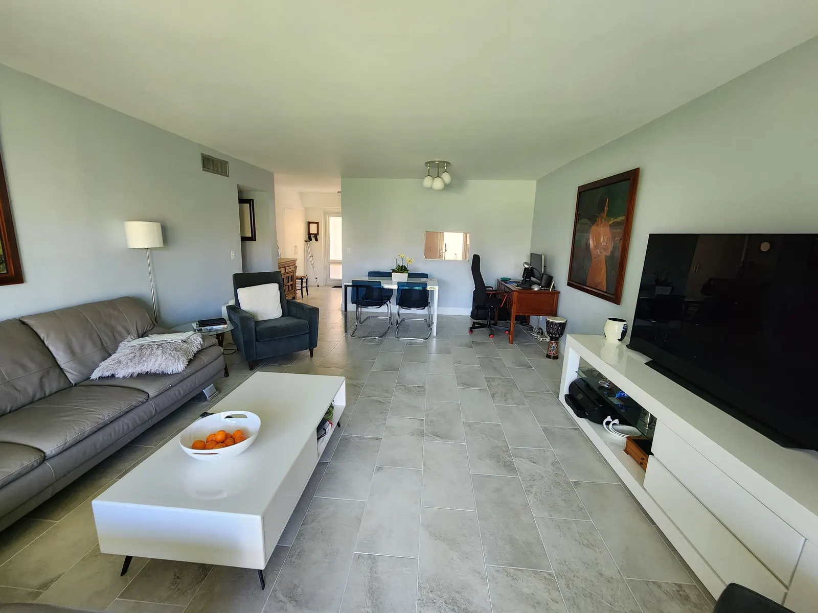 Sala con sofá gris, mesa de centro, comedor y pared de TV