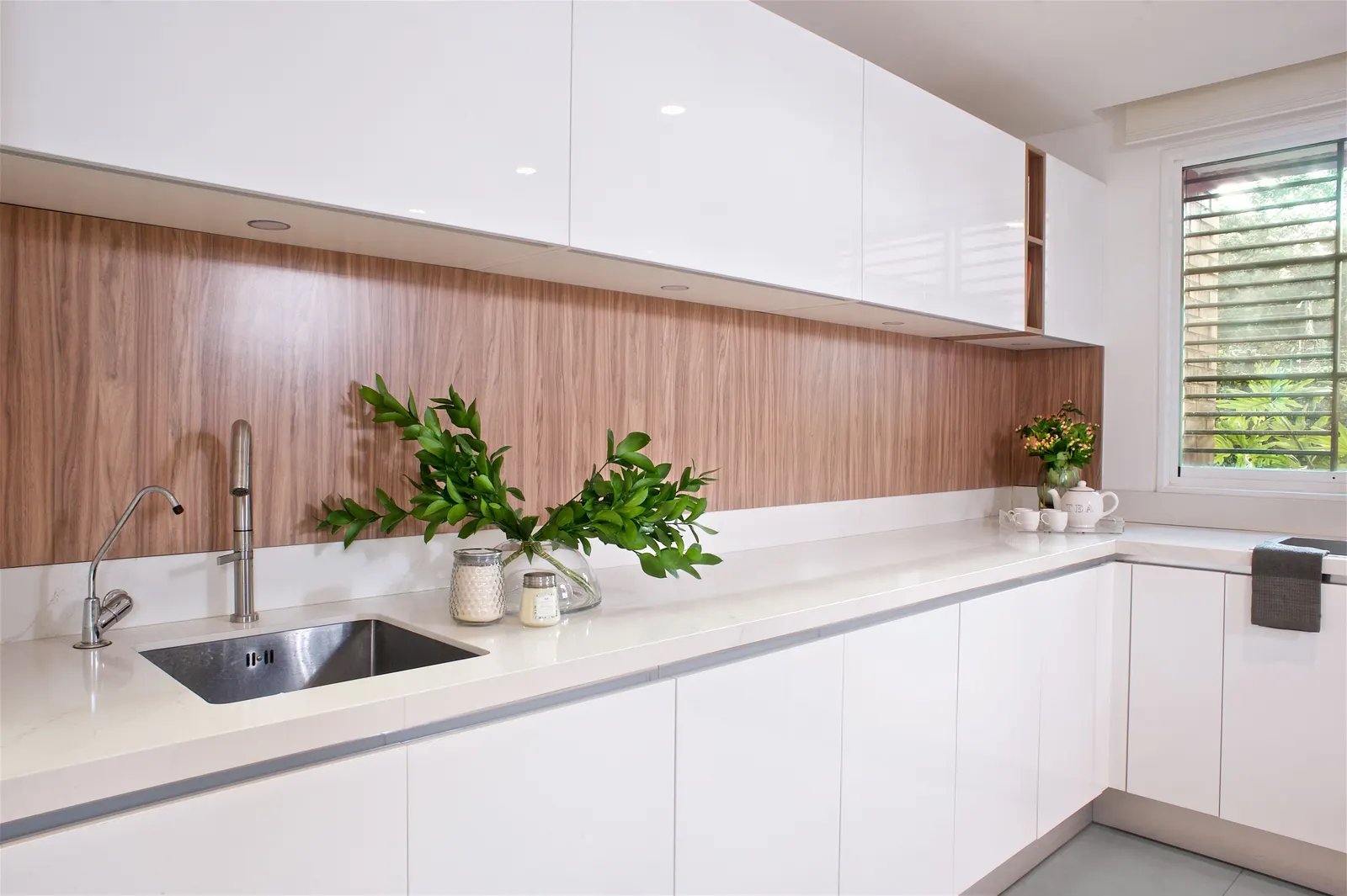 White kitchen with wood backsplash, undermount sink, and window